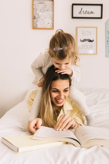 Fille regardant un livre de mère souriante