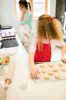 Photo gratuite fille regardant sa mère tout en prenant des biscuits dans la cuisine