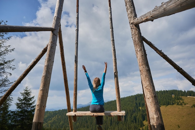 Fille relaxante dans le siège de la balançoire dans les montagnes