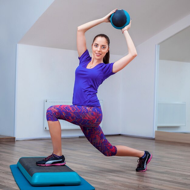 Fille de remise en forme, portant des baskets posant sur une marchepied avec ballon