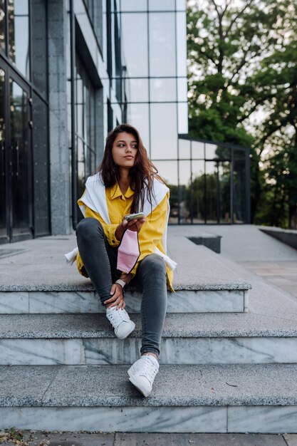 Fille reposant sur les marches. Fille de hipster branchée à la mode et à la mode attrayante marchant dans les rues de la ville.