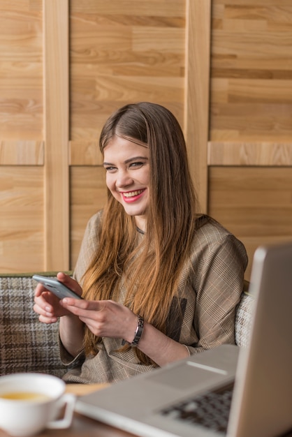 Fille de rire tout en utilisant son téléphone portable