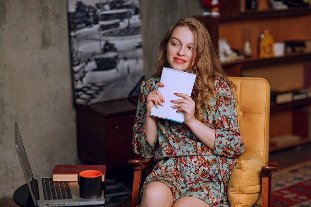 Fille en robe à fleurs assise et tenant un livre.