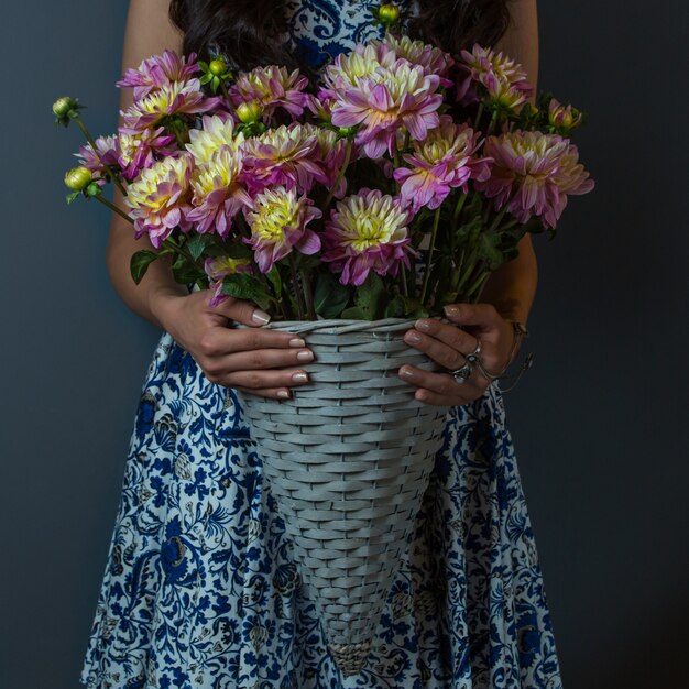 Fille en robe à motifs tenant un bouquet d'oeillets
