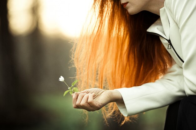 La fille rousse admire la fleur