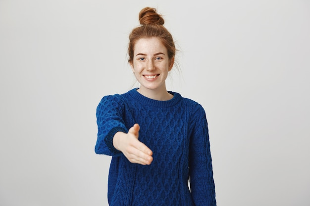 Fille rousse amicale tendre la main pour la poignée de main, saluer la personne