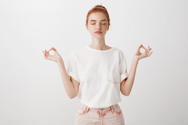 Fille rousse calme restant patiente, ferme les yeux et médite