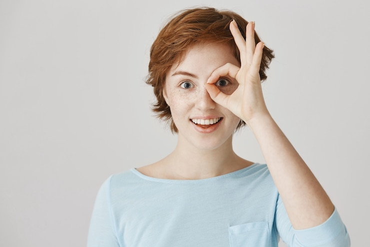 Photo gratuit fille rousse excitée et amusée posant contre le mur blanc