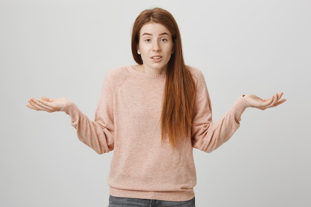 Fille rousse insouciante indécise haussant les épaules