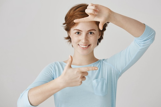 Fille rousse insouciante posant contre le mur blanc