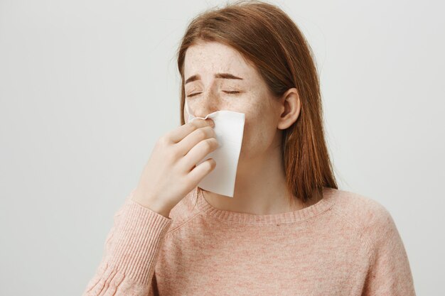 Fille rousse malade éternue dans une serviette