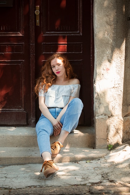 Fille rousse posant devant une porte