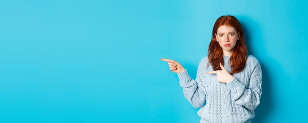 Photo gratuite fille rousse sceptique et mécontente pointant les doigts vers la gauche avec un visage contrarié debout déçu ag