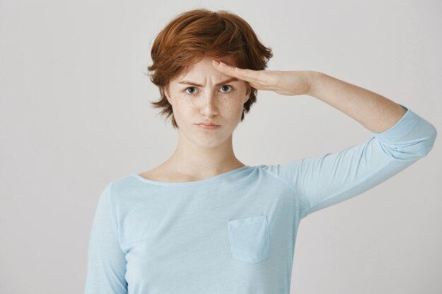 Fille rousse sérieuse saluant comme un soldat