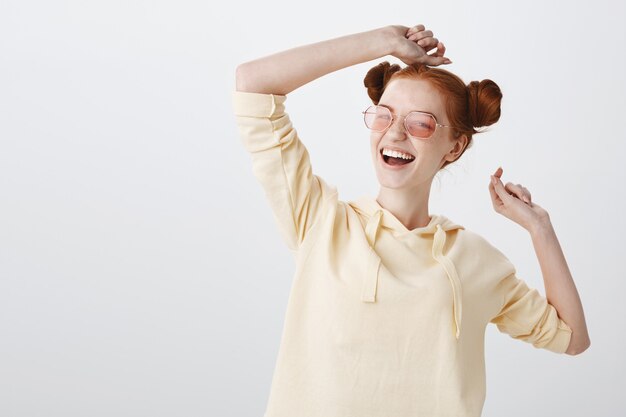 Fille rousse souriante insouciante dans des lunettes de soleil profitant de l'été