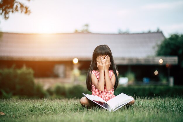 Fille s&#39;ennuie lire dans le jardin de la maison