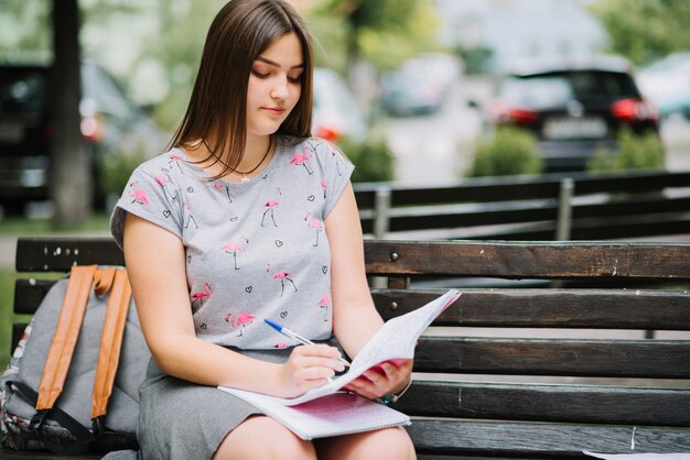 Fille avec sac à dos et études sur banc