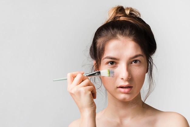 Fille se appliquant un produit cosmétique