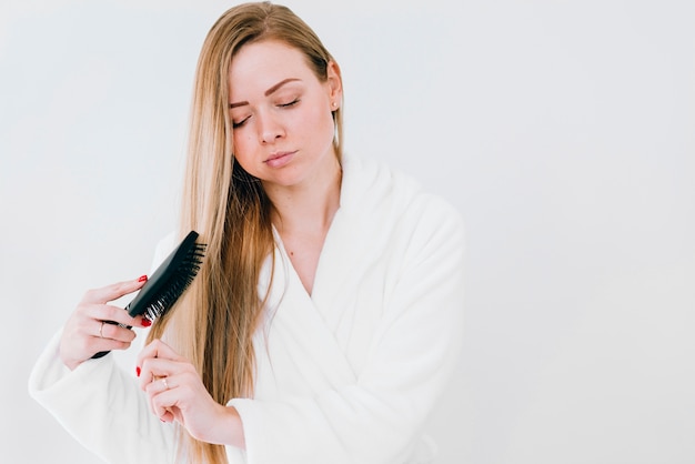 Fille se brosser les cheveux à la salle de bain