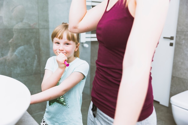 Fille se brosser les dents près de la mère