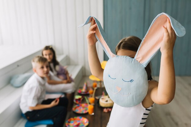 Fille se cachant derrière un coussin de lapin