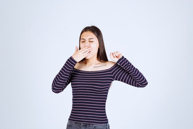 La fille se sent épuisée et a l'air endormie.