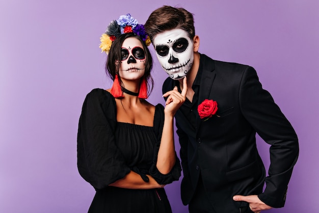 Photo gratuite fille sérieuse en costume de mascarade posant sur fond violet. funny couple en tenue de carnaval à la recherche d'appareil photo.