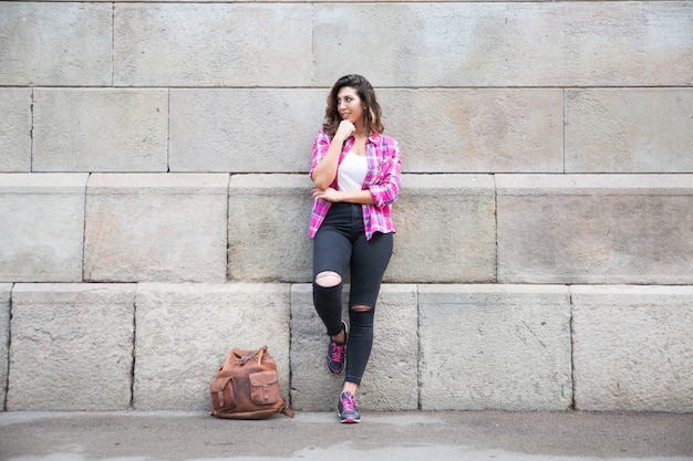 Fille sexy et souriante appuyée sur un mur de construction