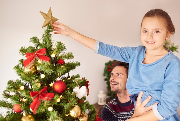 Fille et son papa décorant le sapin de Noël