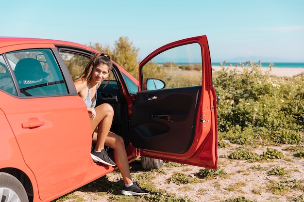 Fille sortir de la voiture et regarder la caméra