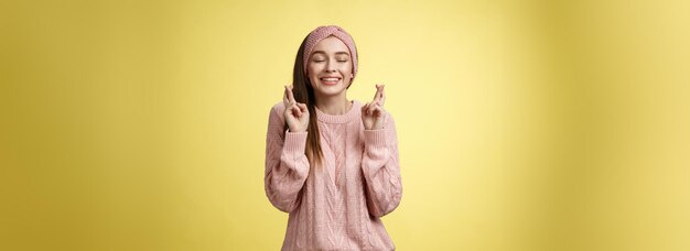 Fille souhaitant le bien-être voulant que son rêve se réalise doigts croisés rêveux yeux fermés attendant le miracle