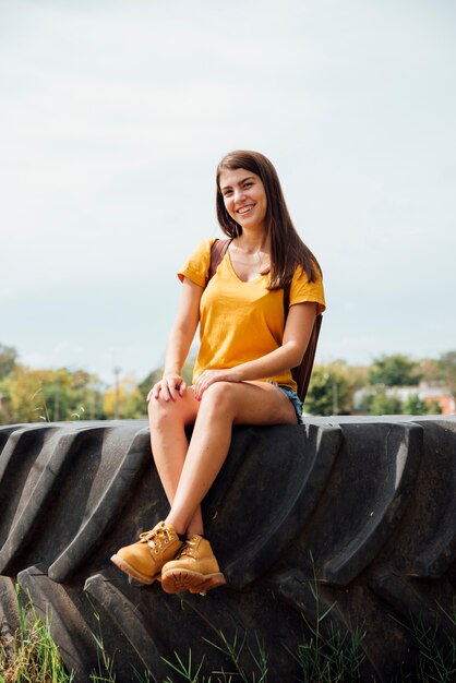 Fille souriante assise sur une roue de tracteur