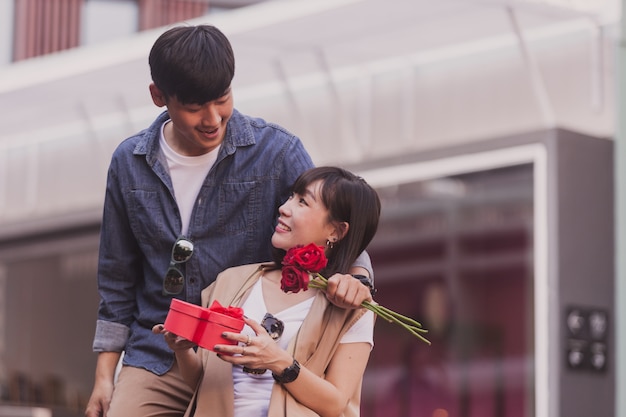 Fille souriante avec une boîte de chocolats et des roses