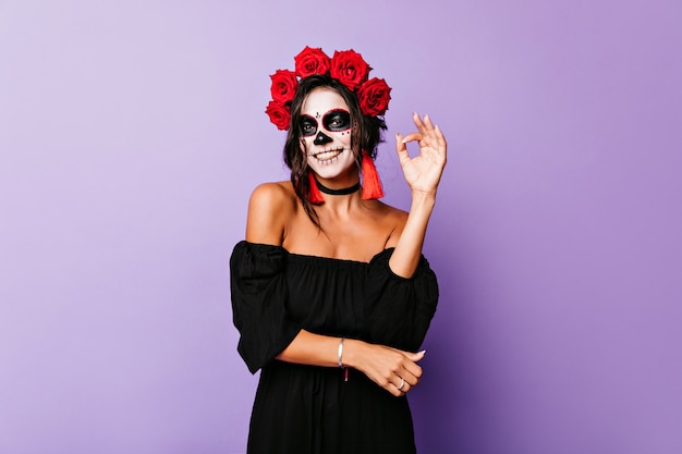 Photo gratuite fille souriante bronzée aux cheveux noirs refroidissant sur le mur violet. blithesome jeune femme en costume de mascarade appréciant la séance photo.