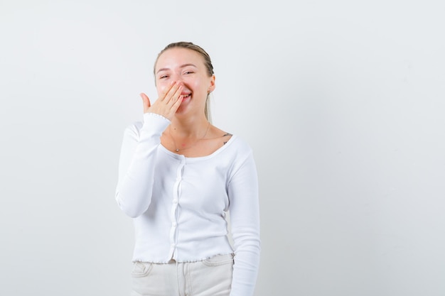 Une fille souriante ferme la bouche sur fond blanc