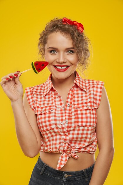 Une fille souriante gardant une sucette ressemble à un morceau de pastèque