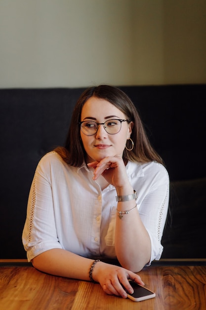 Fille souriante, passer du temps dans un café de rue à l'aide de gadget numérique