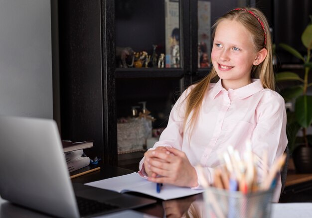 Fille souriante tout en ayant un cours en ligne