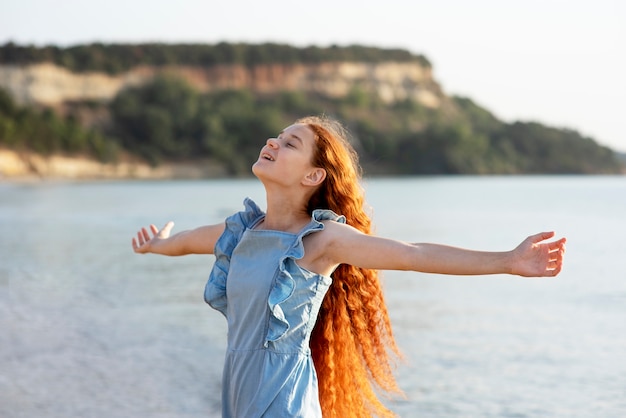 Fille souriante vue de côté au bord de la mer