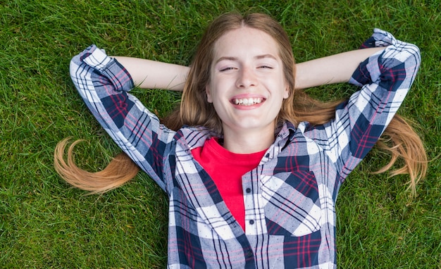 Photo gratuite fille souriante vue de dessus restant sur l'herbe