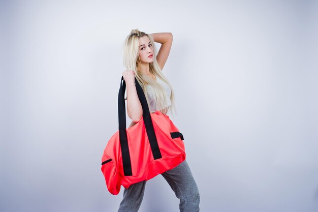 Fille sportive blonde avec grand sac de sport posé au studio sur fond blanc