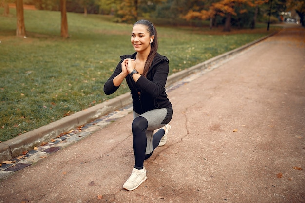 Fille sportive dans une formation en haut noir dans un parc en automne