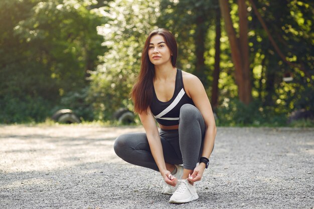 Fille sportive dans un top noir dans un parc d'été