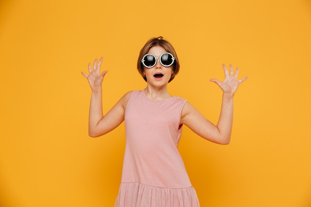 Fille surprise avec les mains levées à la recherche d'appareil photo