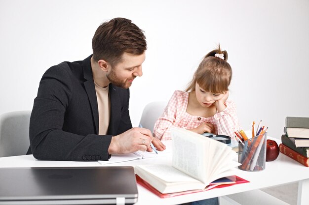 Fille avec le syndrome de Down étudiant avec son professeur à la maison