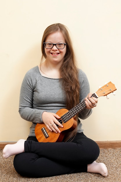 Fille avec le syndrome de Down tenant la guitare et souriant