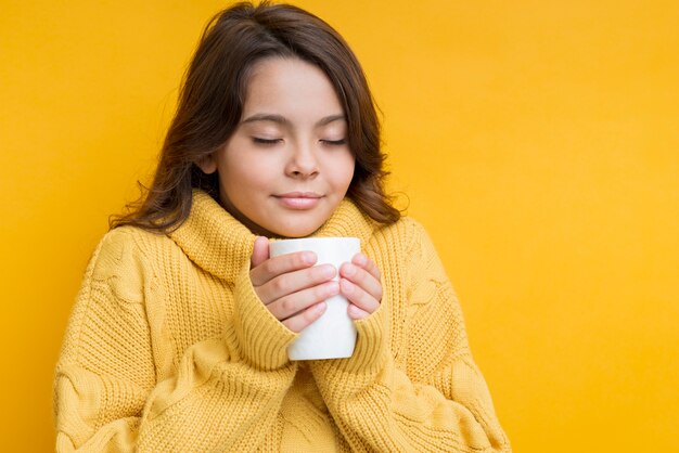 Fille avec une tasse dans les mains et les yeux fermés