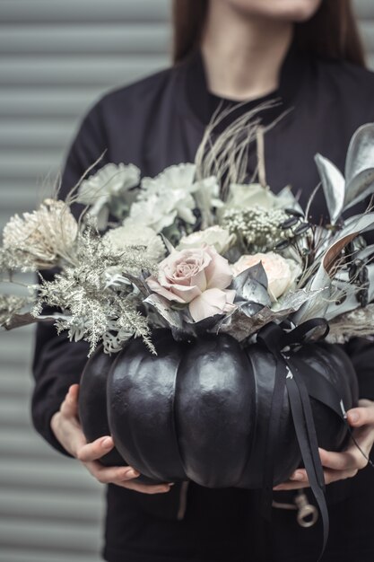 Fille tenant un arrangement floral dans une citrouille