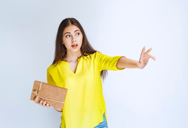 Fille tenant une boîte-cadeau en carton et désireuse d'en prendre une autre.