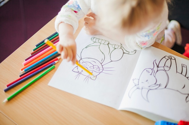 Fille tenant un crayon assis à table